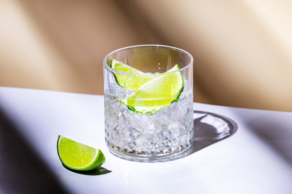 Strong alcoholic cocktail drink with craft rum, sugar syrup and lime. Beige background